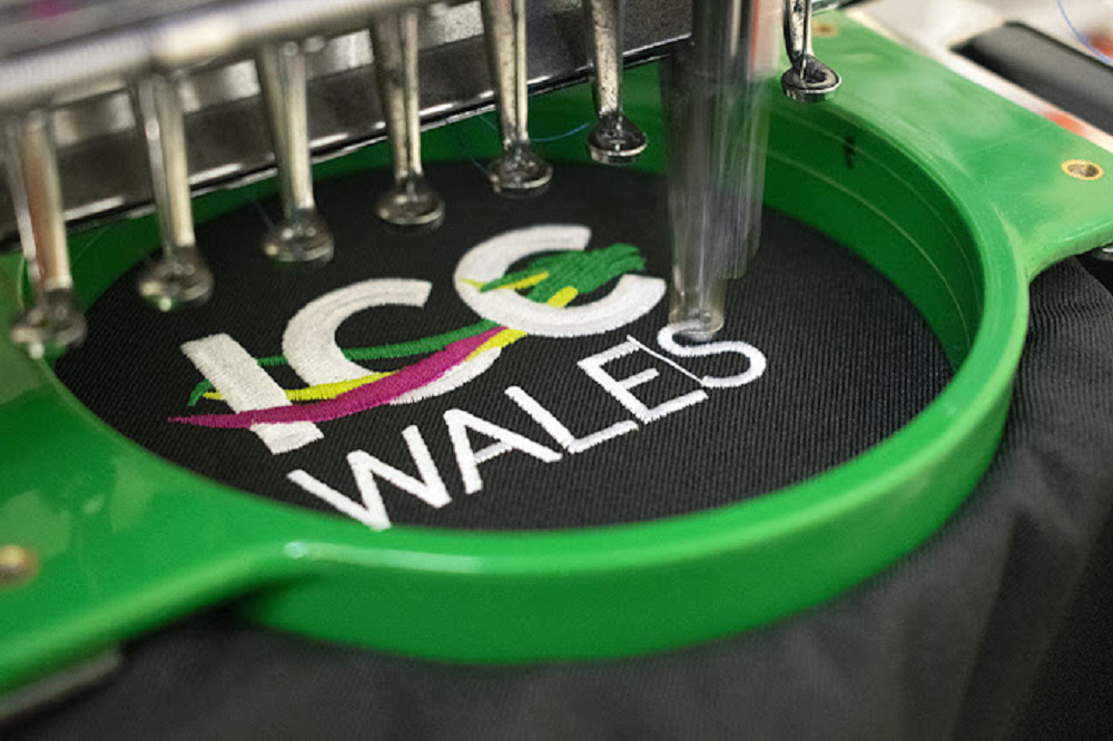 Business logo being embroidered onto a polo shirt at Delaware County Shirt Printing, Upper Darby PA